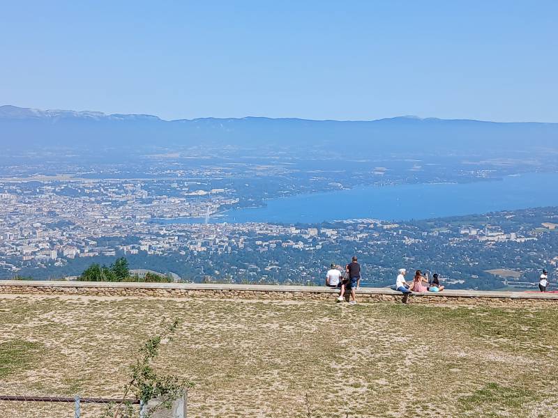 Au dessus de l’esplanade, quelques familles observent la vue sur la vallée ; on voit bien le jet d’eau de Genève.
