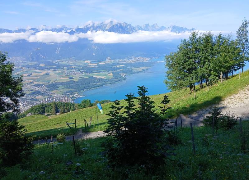Aire de décollage de parapentes, avec manche à air, on distingue un parapentiste sur la gauche. En arrière-plan, le Léman à l’embouchure du Rhône.