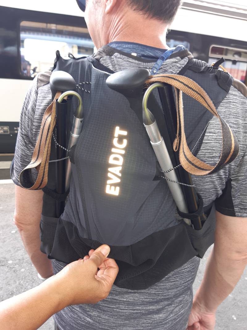 Mon collègue, de dos, portant son sac de trail EVADICT avec ses batons. Photo prise sur un quai de gare.